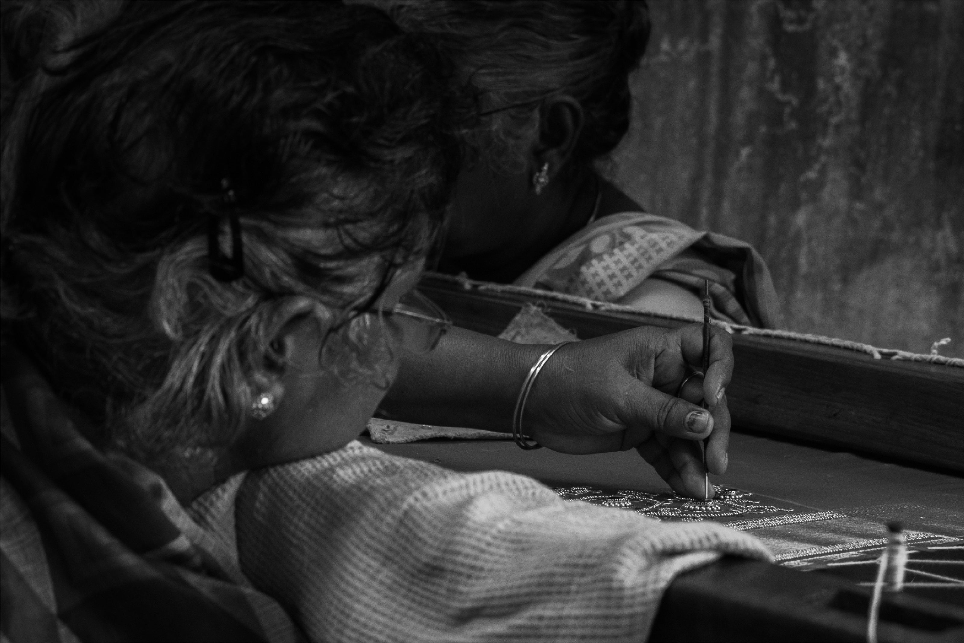 A black and white photo of a women doing embroidery.